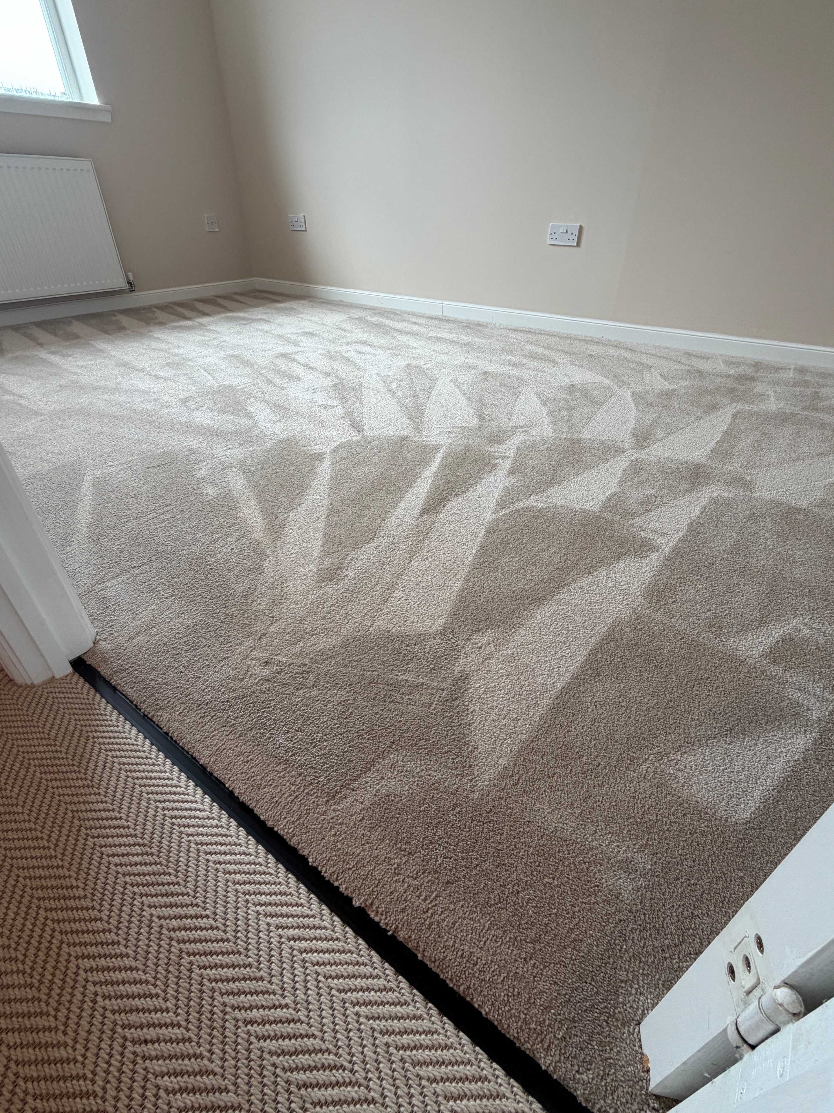 Hallway with warm beige patterned carpet and herringbone stair runner